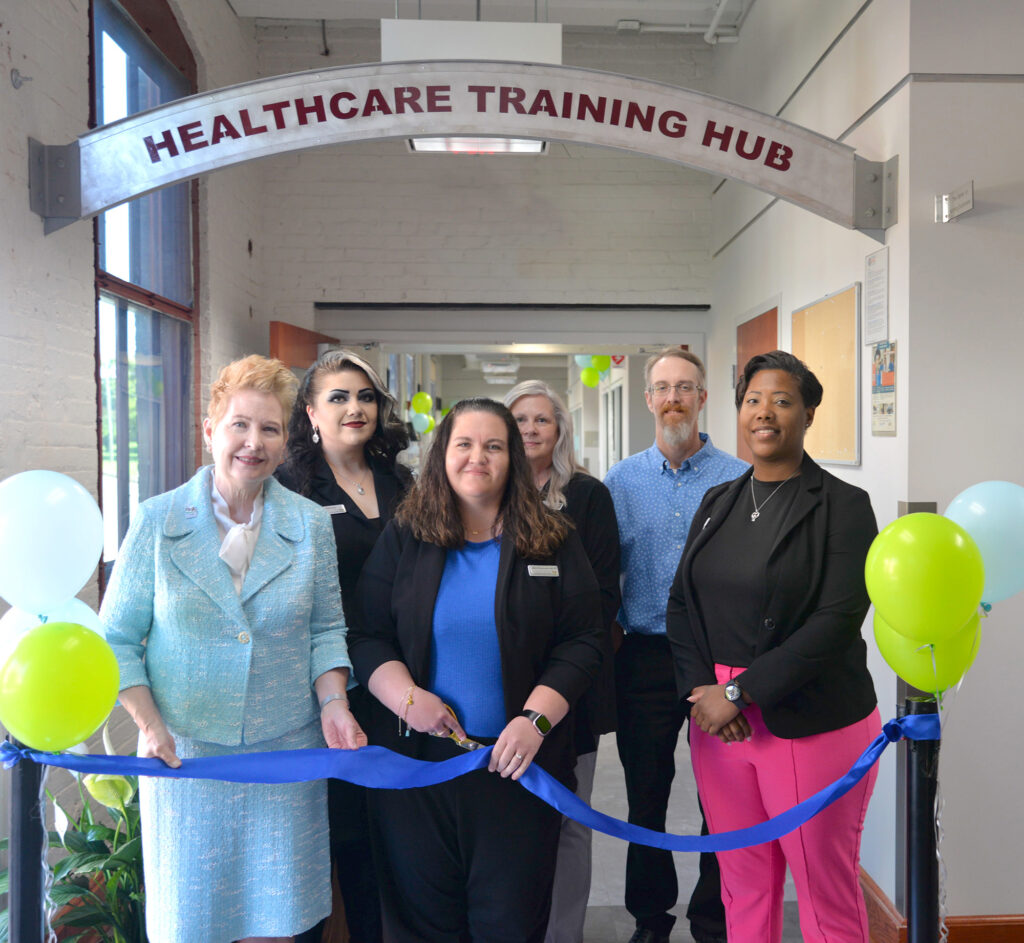 utting the Ribbon on the newly named Healthcare Training Hub (first row, l-r): Dr. Betty Adams (Executive Director), Kimberly Throckmorton (Healthcare Training Hub Manager), Natasha Lipscomb (Southside VA AHEC Director) (back row, l-r): Ericka Poole (Administrative Assistant), Teresa Slabach (Healthcare Instructor), and Robert Jordan (Simulation Technologist)